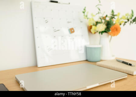 High angle view of laptop computer with diary and pen on wooden desk in office Stock Photo