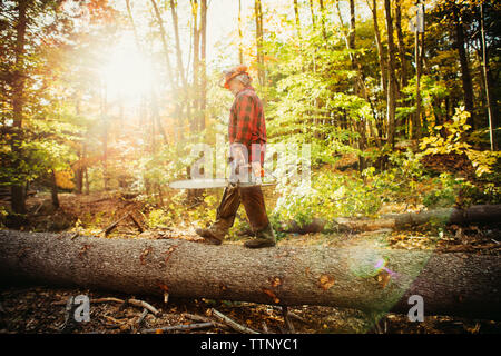 Side view of lumberjack walking on log in forest Stock Photo