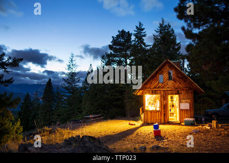 Illuminated wooden cabin in forest at night Stock Photo