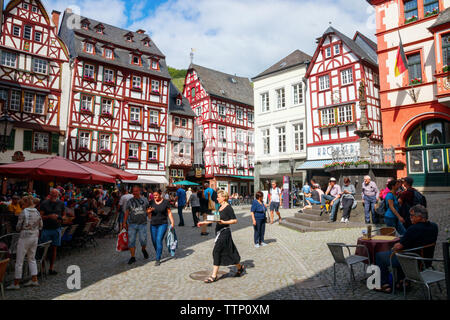 Sightseeing tourists at the Market Square with half-timbered houses on a sunny afternoon. Bernkastel-Kues, Rhineland-Palatinate, Germany. Stock Photo