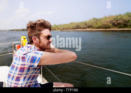Thoughtful man looking at river while sitting in boat Stock Photo
