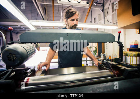 Male worker using printing machine at workshop Stock Photo