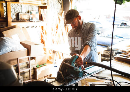 Artist using circular saw on wooden plank at workshop Stock Photo