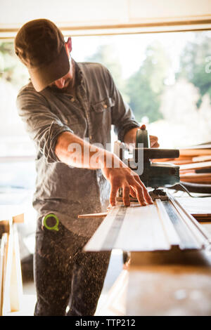 Artist using circular saw on wooden plank at workbench in workshop Stock Photo