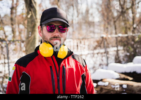 Portrait of carpenter wearing protective workwear standing in backyard during winter Stock Photo