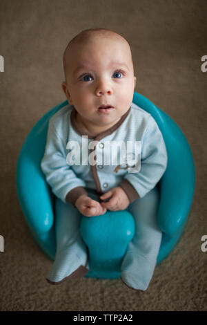 Baby boy looking up while sitting on potty at home Stock Photo