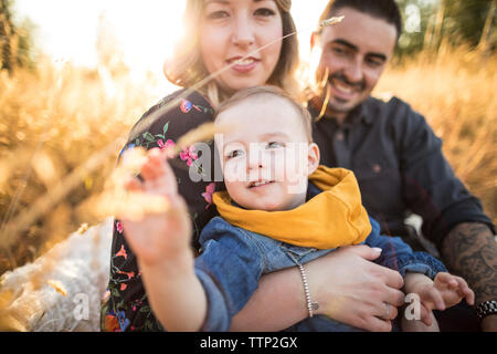 Happy family having picnic on field during sunset Stock Photo