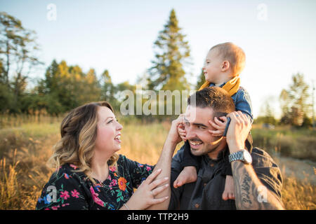 Mother looking at son sitting on father's shoulders Stock Photo