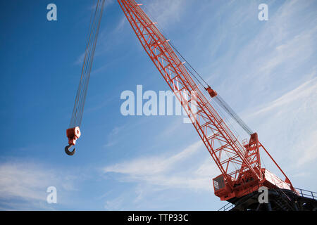 Low angle view of hook hanging on crane against sky Stock Photo