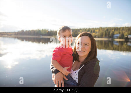Portrait of mother and son against lake during sunny day Stock Photo
