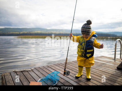 Full length of baby boy wearing raincoat and life jacket while holding