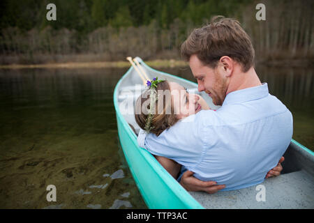 Young couple looking each other face to face while relaxing in canoe on lake Stock Photo