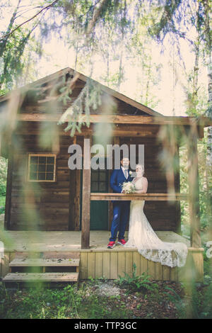 Portrait of newlywed couple standing in porch at forest Stock Photo