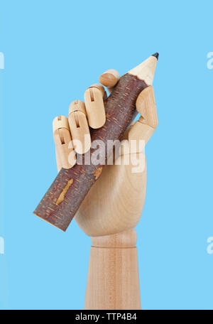 Wooden hand holding big pencil on white background Stock Photo