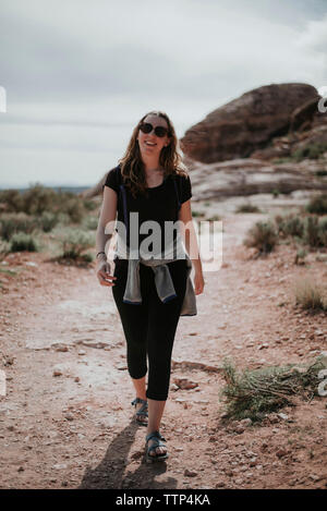 Female hiker in sunglasses walking on field at Red Rock Canyon National Conservation Area Stock Photo