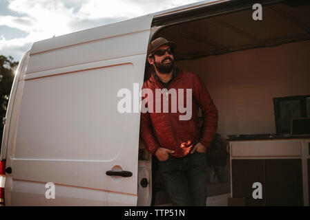 Man wearing cap and sunglasses while standing in motor home Stock Photo