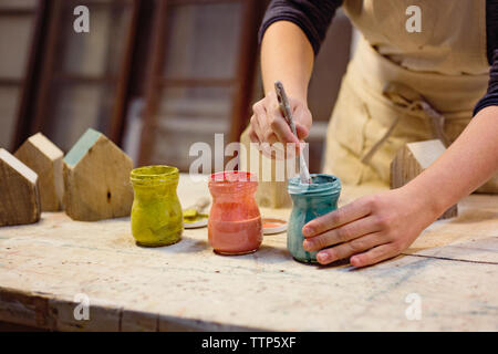 Midsection of carpenter coloring wooden model houses in workshop Stock Photo