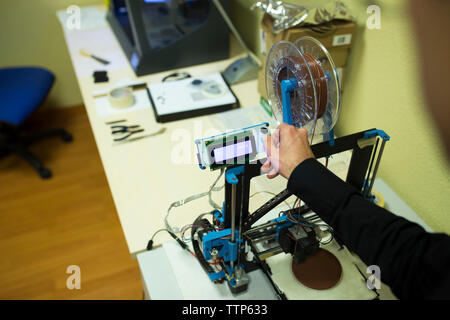 Cropped hand of engineer examining 3D printer on table in office Stock Photo