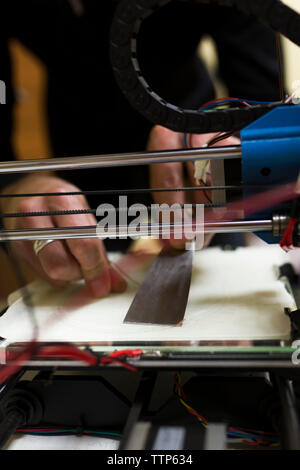 Cropped hands of male engineer fixing 3D printer on table Stock Photo