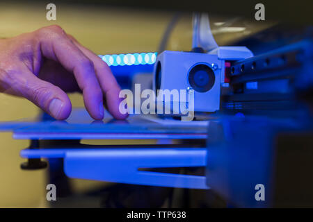 Cropped hand of engineer examining 3D printer in office Stock Photo