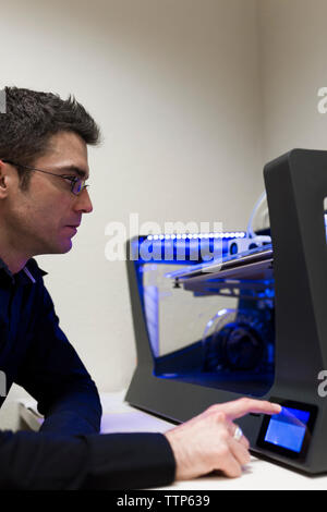 Engineer operating 3D printer on table in office Stock Photo