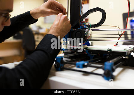Male engineer fixing 3D printer on table Stock Photo