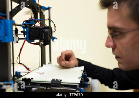 Confident engineer examining 3D printer on table Stock Photo