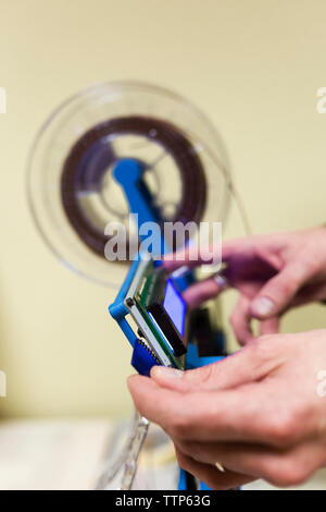 Cropped hands of male engineer fixing 3D printer in office Stock Photo