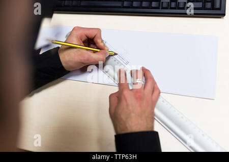 Cropped hands of engineer drawing on paper at desk in office Stock Photo