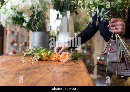 Unrecognisable woman preparing bouquet of flowers at flower desk shop Stock Photo