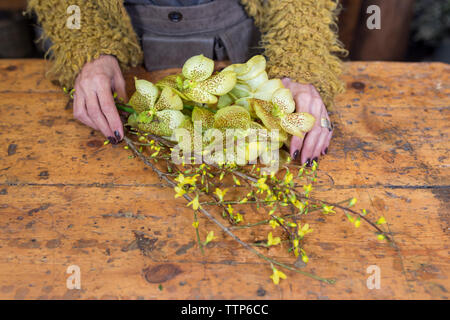 cropped image of woman hands holding yellow flowers at desk Stock Photo