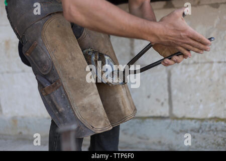 Unrecognisable young farrier bending down horse shoe Stock Photo