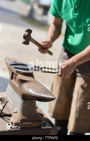 Farrier shaping horse shoe on an anvil Stock Photo
