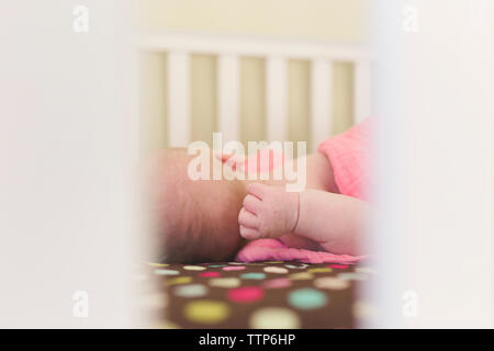 Close-up of baby girl sleeping in crib seen through railing at home Stock Photo