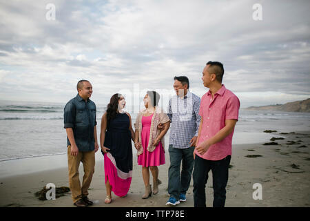 Happy family walking on shore at beach against sky Stock Photo
