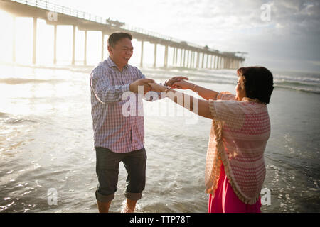 Couple dancing on shore at beach Stock Photo