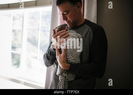 Father carrying newborn daughter while standing at home Stock Photo