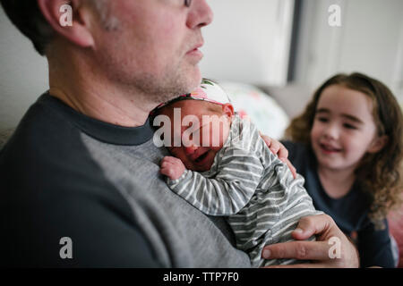 Father comforting crying baby girl by daughter at home Stock Photo