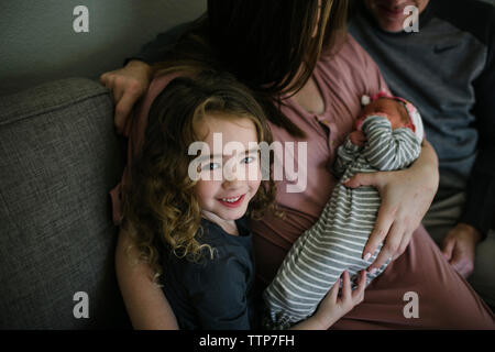 High angle portrait of smiling girl with parents and sister on sofa at home Stock Photo