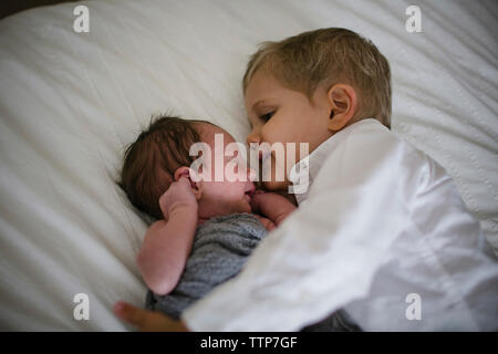 High angle view of boy lying by newborn brother on bed at home Stock Photo