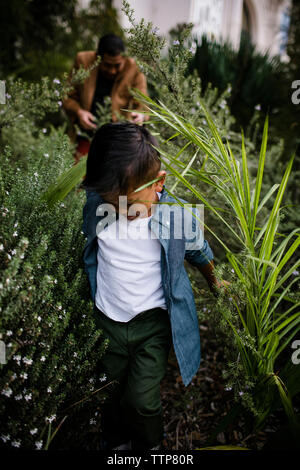 Close-up of son walking amidst plants against father in Balboa Park Stock Photo