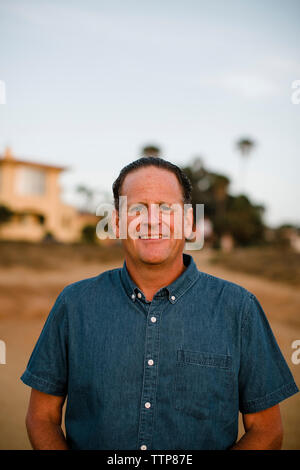 Portrait of smiling man standing on cliff against sky during sunset Stock Photo