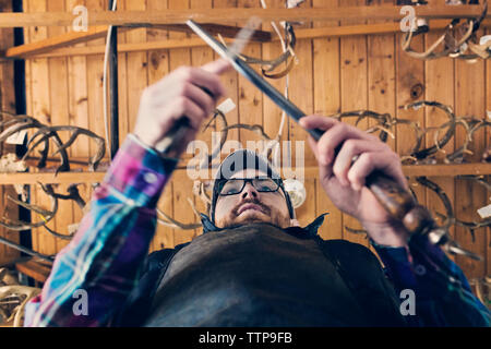 Directly below shot of man sharpening knife Stock Photo