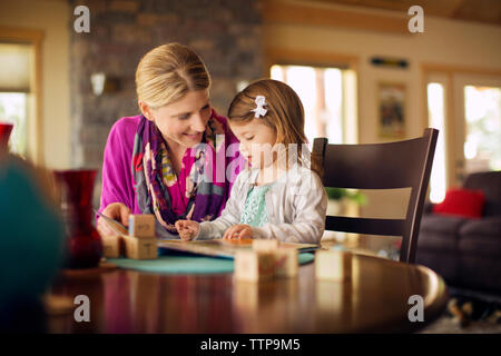 Mother teaching daughter on table at home Stock Photo