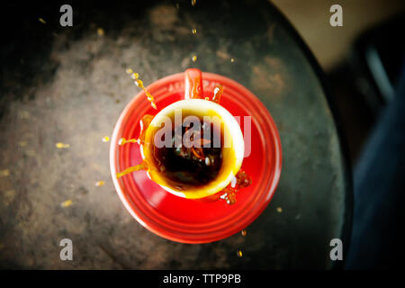 Overhead view of coffee splashing in cup on table Stock Photo