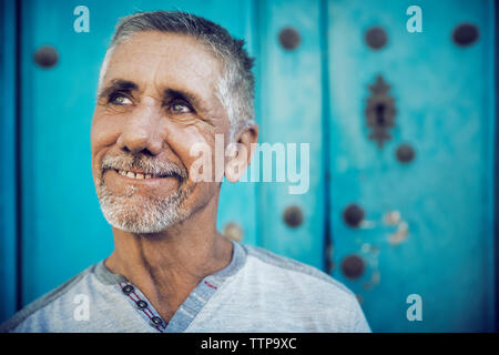 Close-up of thoughtful man against blue wall Stock Photo