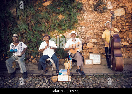 Street musicians playing musical instruments against stone wall Stock Photo