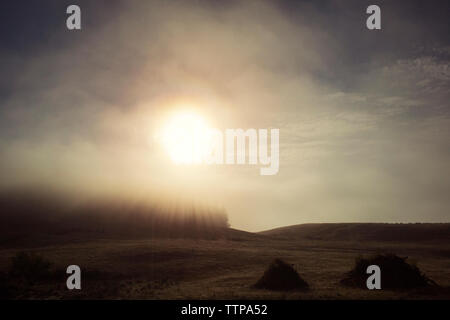 Sun shining over landscape during foggy weather Stock Photo