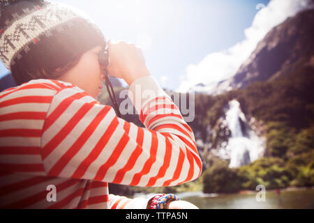 Side view of boy looking through binocular on sunny day Stock Photo