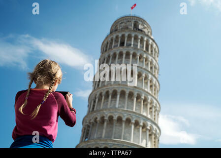 Rear view of girl photographing Leaning Tower of Pisa against sky Stock Photo